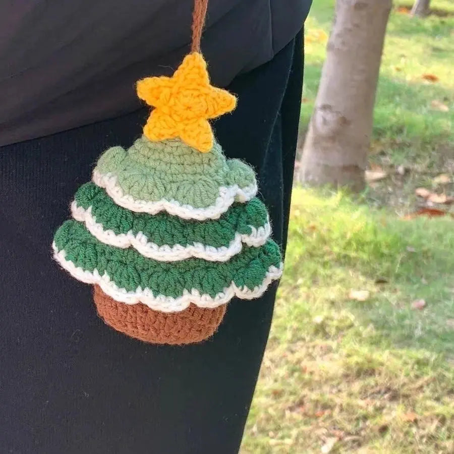 A crochet Christmas tree with yellow stars on top, hanging on pants.