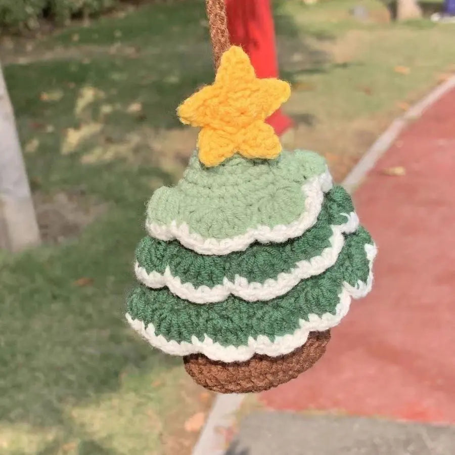 A handcrafted crochet Christmas tree ornament made from green and white yarn, featuring a yellow star on top and hanging from a woven basket